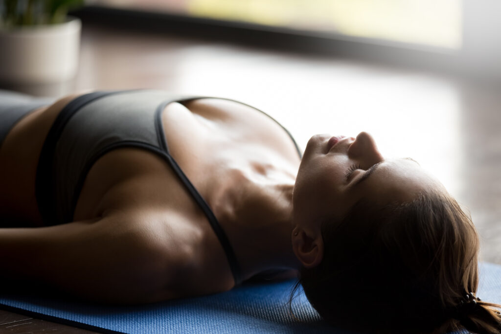 Mujer tumbada realiza ejercicio de relajación y respiración